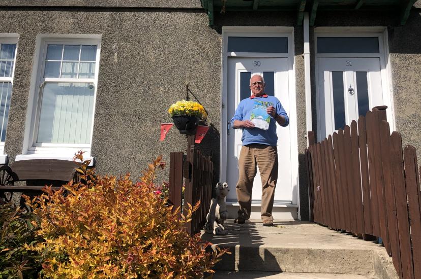 A client holds a brochure delivered by Vannin Travel's Tony Lawrence
