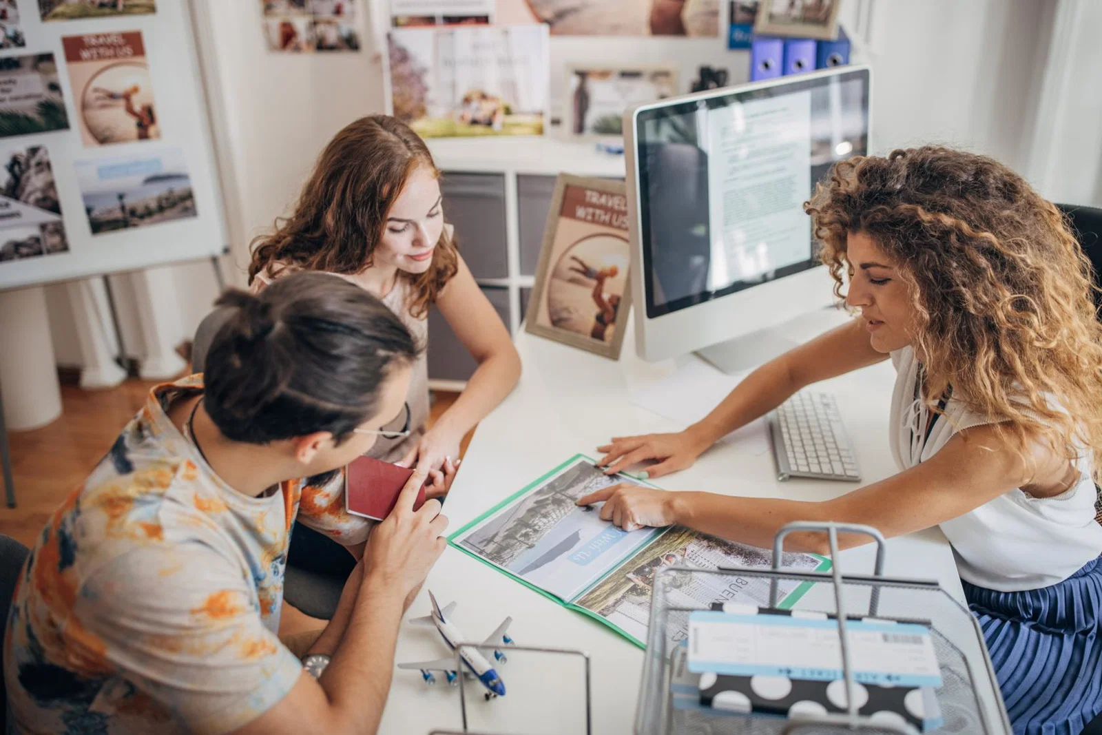 A travel agent helps a young couple with an enquiry