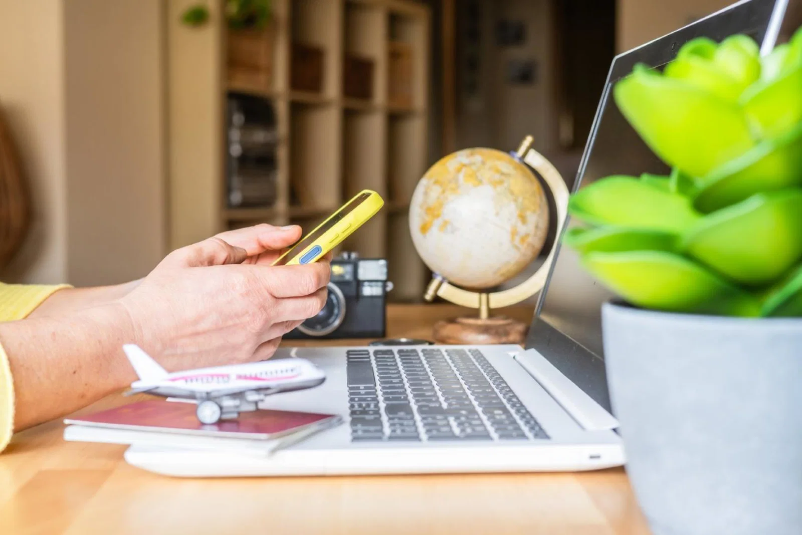 Person using a phone sitting at a laptop