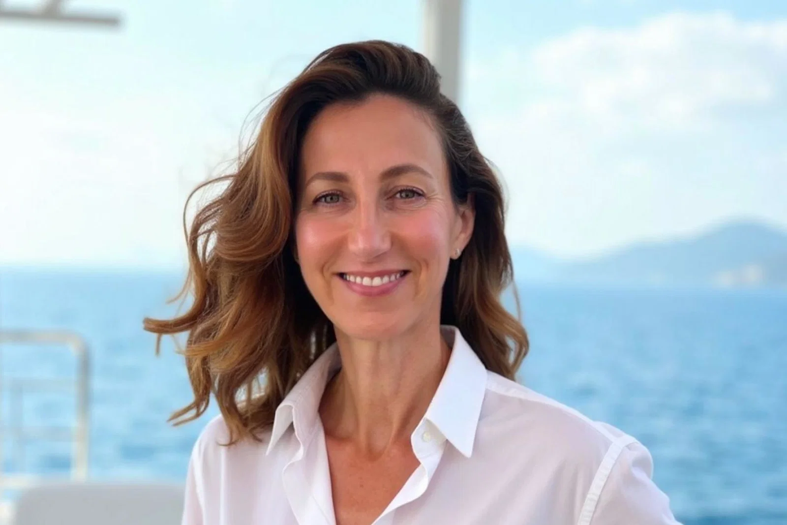 Smiling middle-aged woman with long brown hair and a white shirt 
