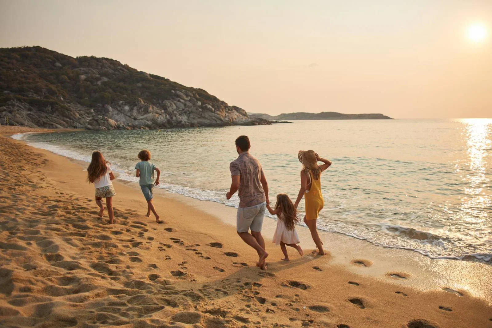 A family of five frolic happily on a sunny beach