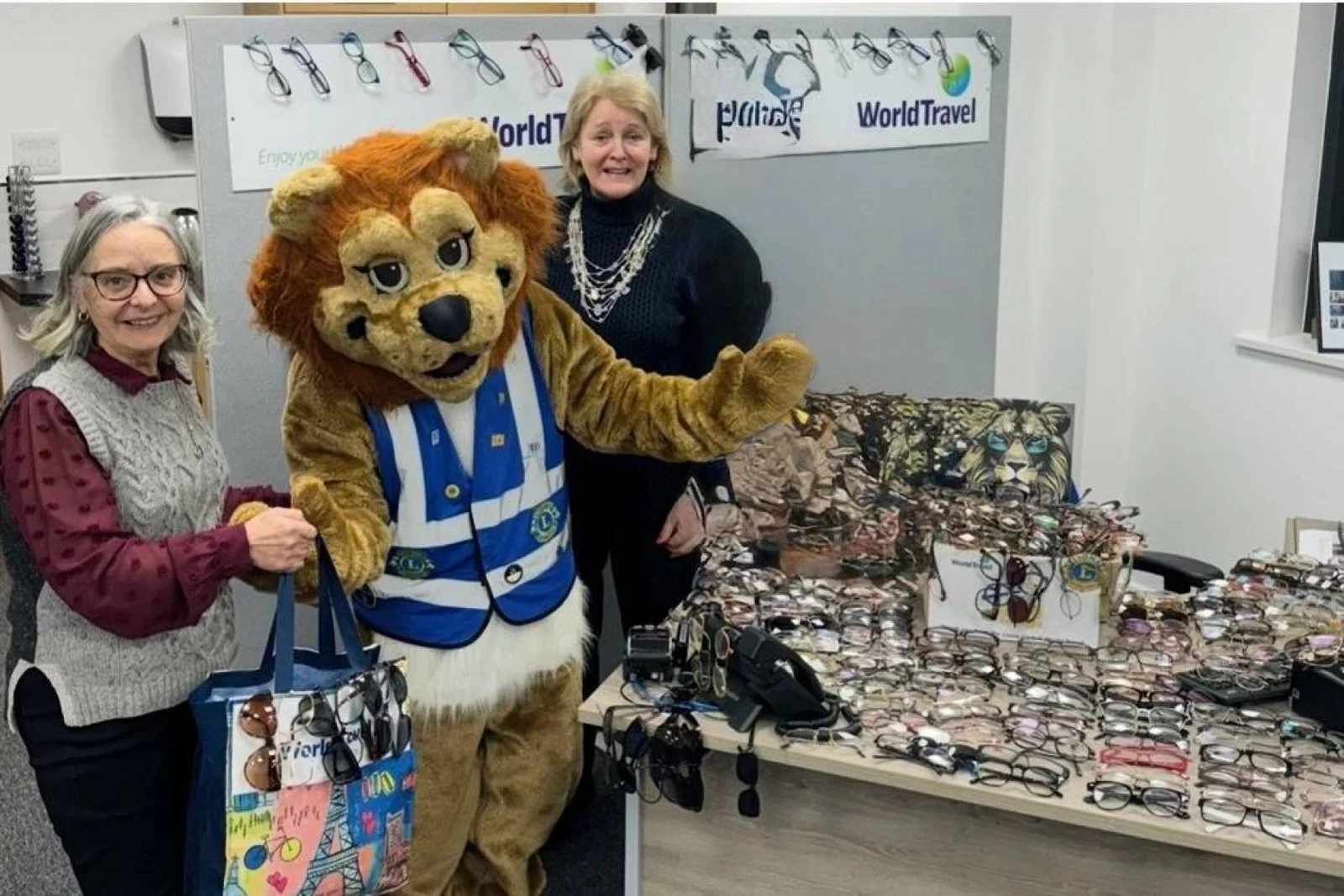 Team at Travel World Jersey next to Lions Club of Jersey mascot and collected glasses