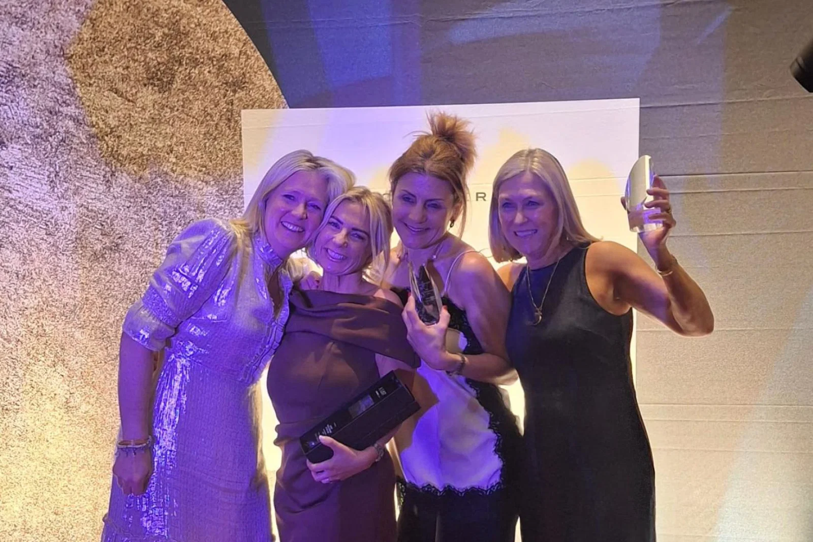Four smiling women at an awards show 