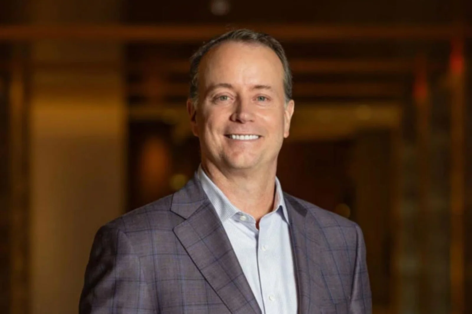 Headshot of white man smiling in grey suit 