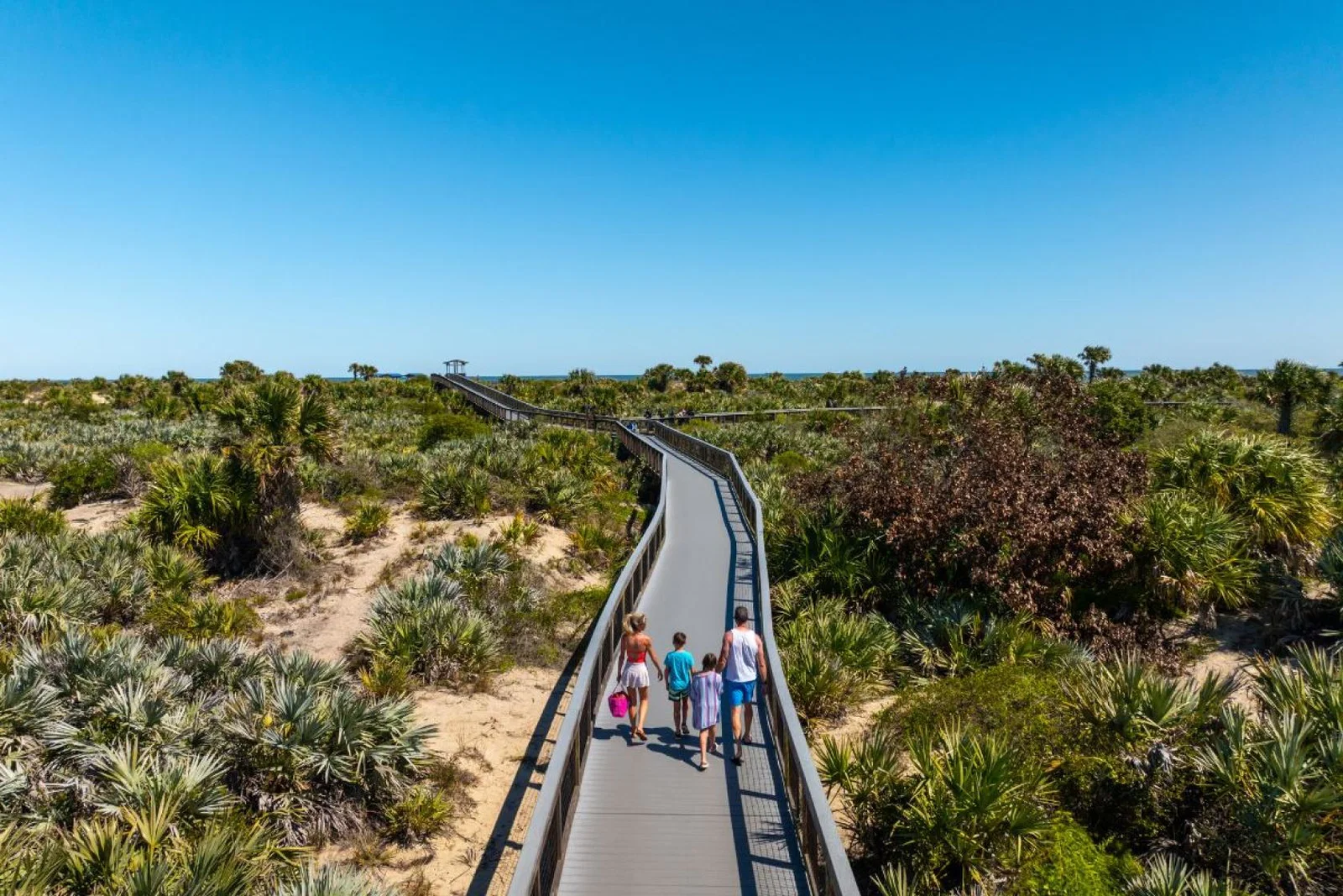 People walking along a boardwalk to the sea