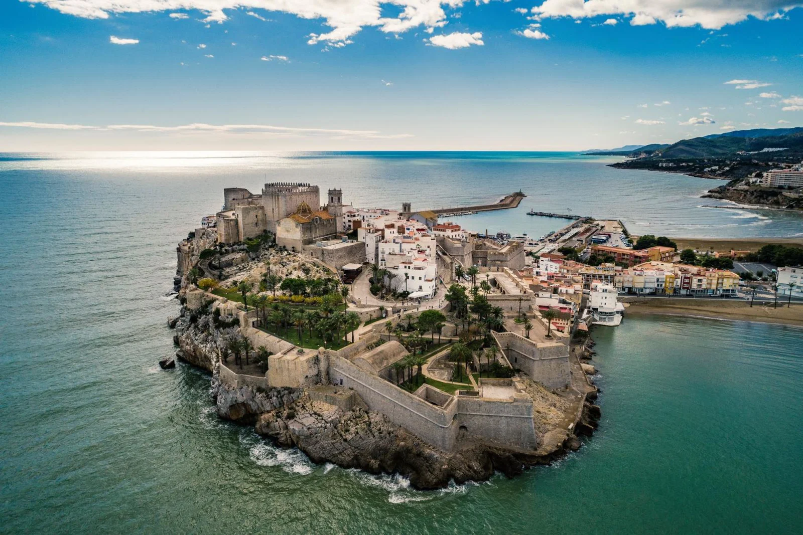 A medieval stone fortress built on a high rocky peninsula, overlooking the blue Mediterranean Sea under a clear sky