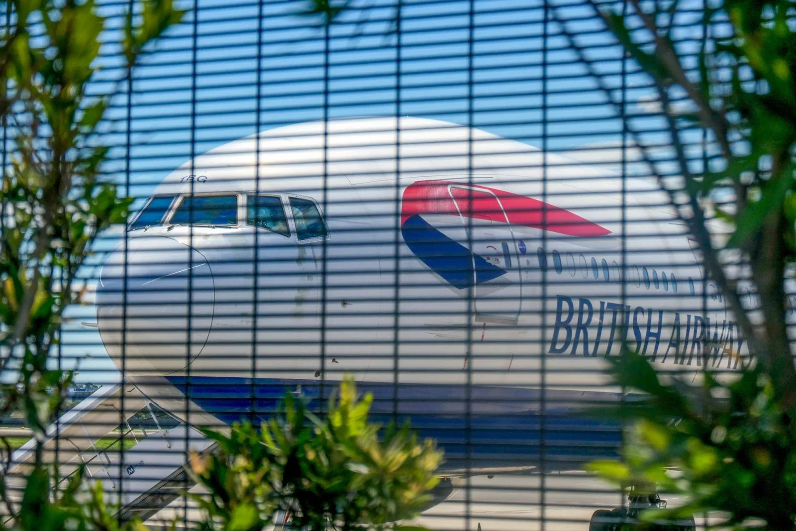 A grounded British Airways aircraft seen through a mesh fence