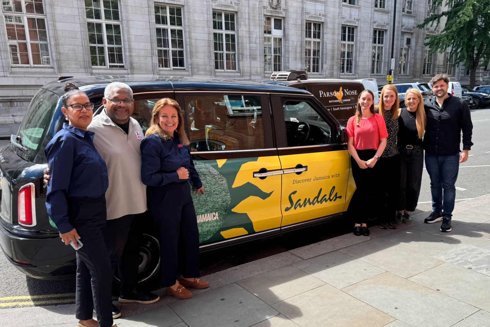 Team members from the Jamaica Tourist Board and Unique Vacations UK stand around a dual-branded taxi in London