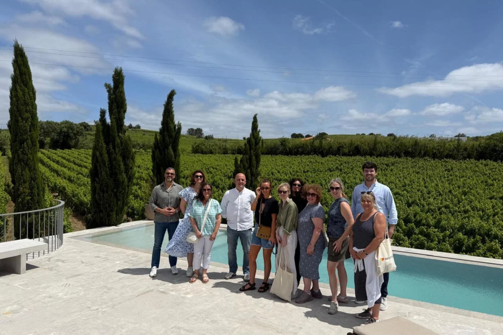 Group of travel agents standing and smiling by a private outdoor pool in rural Portugal 