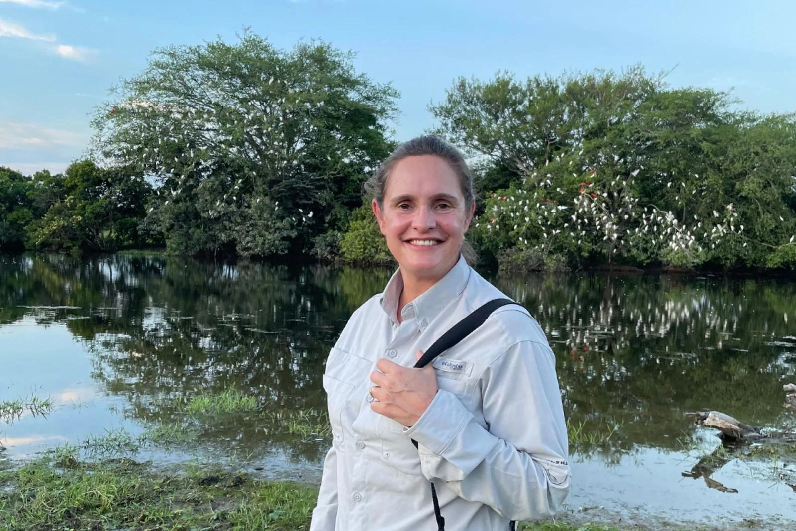 Woman smiles with luscious tree full of Ibis behind her