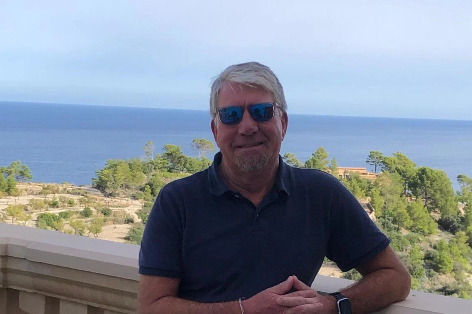 White man smiling in front of sea background
