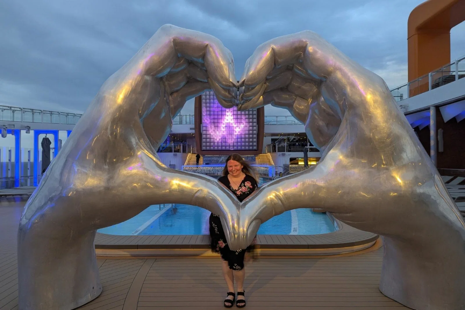 Maria Milne poses besides giant hands shaped in a love heart