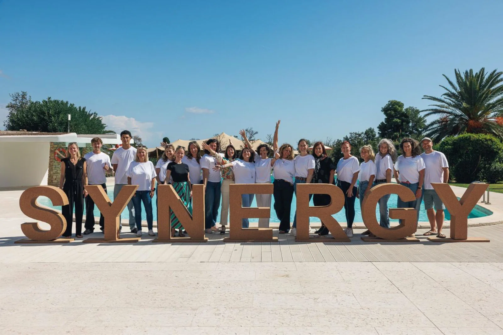 Group of people in front of a large sign that says 'Synergy' 