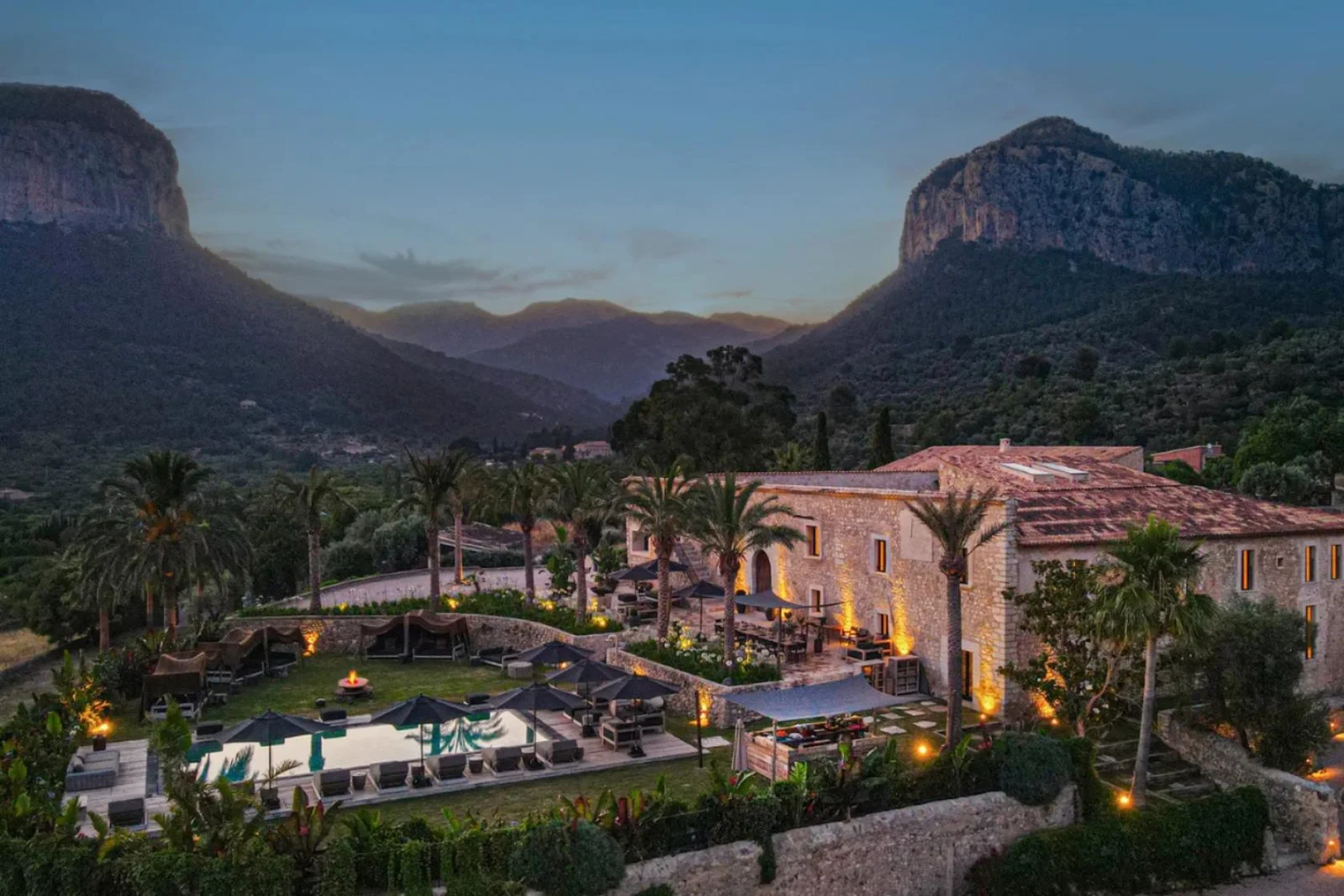Aerial shot of luxurious chateau with lush gardens and rugged moutaineous background 