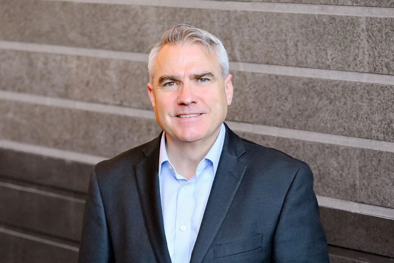 Man with grey hair and suit smiling 