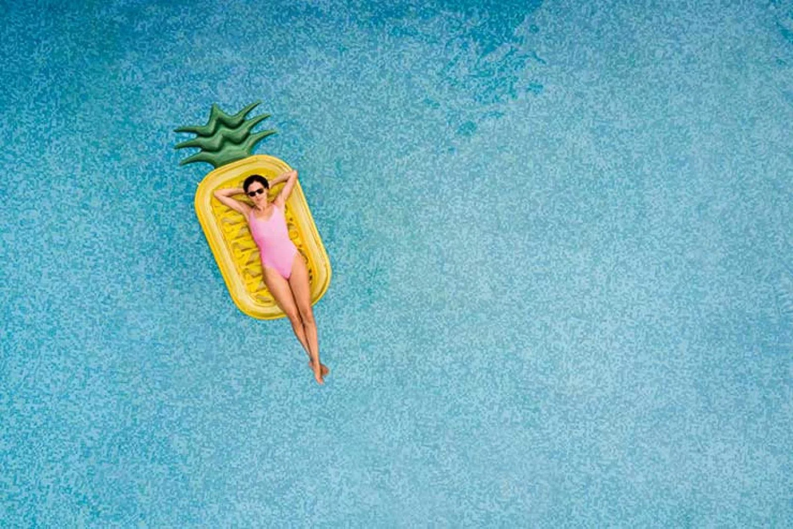 Woman floating on a pineapple lilo
