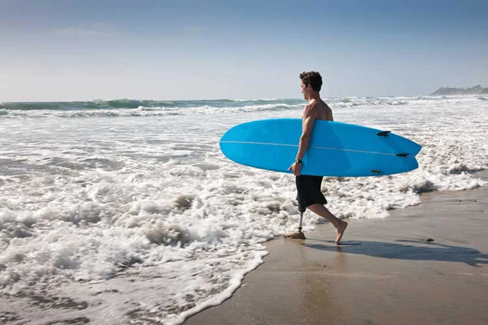 Man with surfboard entering sea