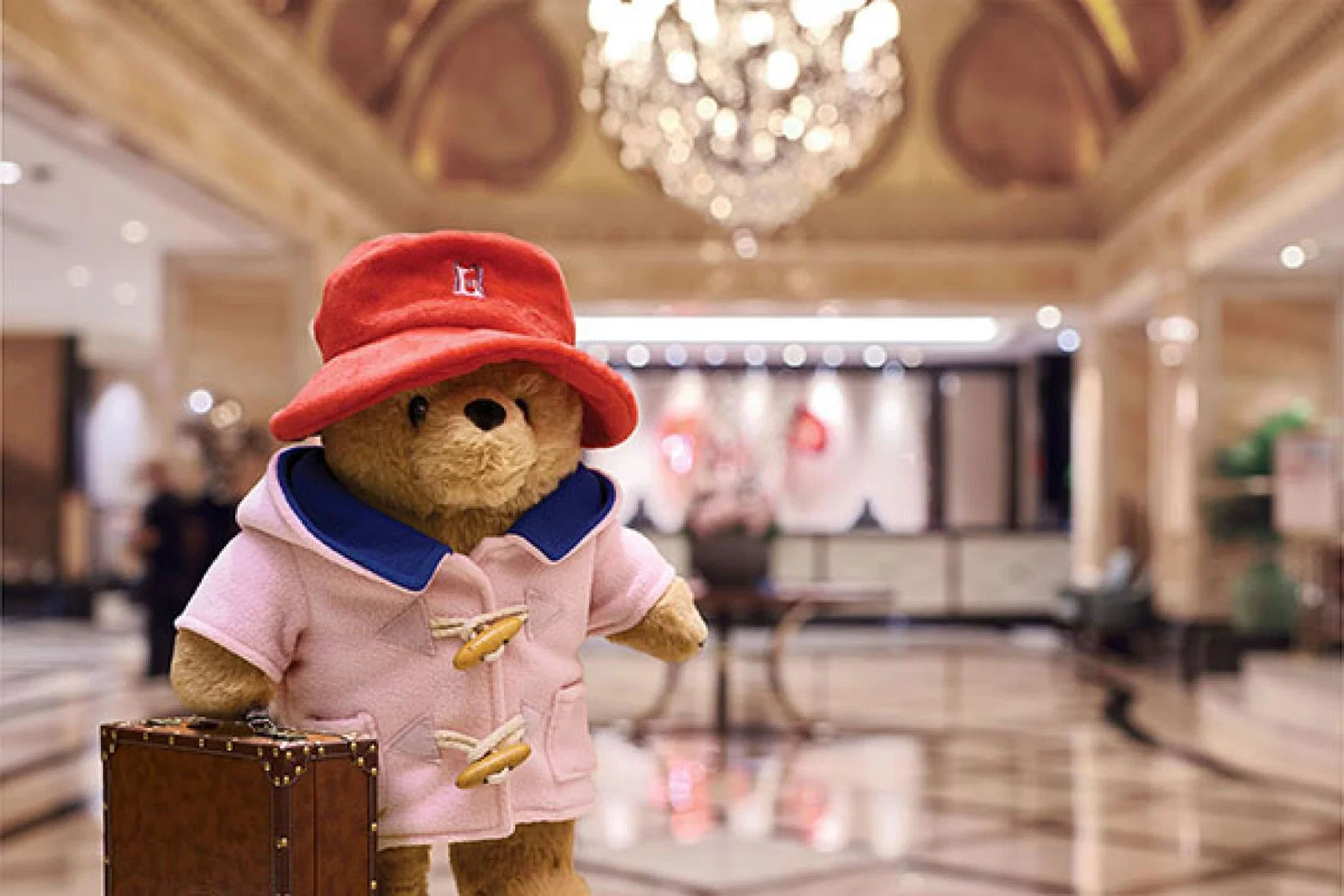 Paddington has swapped his traditional blue duffle coat for a new Langham-pink version