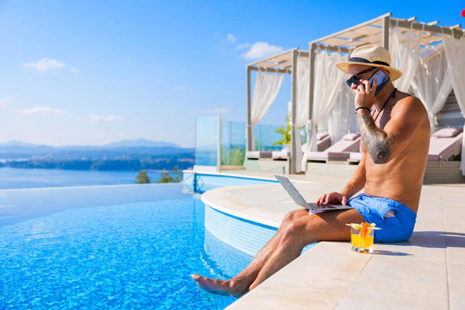 Holidaymaker using laptop by pool