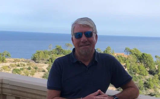 White man smiling in front of sea background