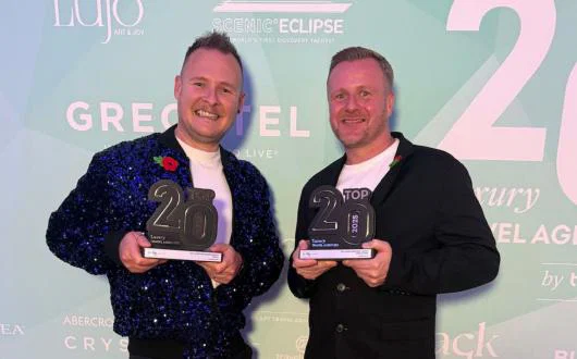 Two men holding trophies and smiling 