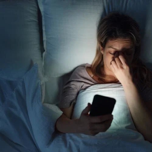 Woman in bed looking at phone
