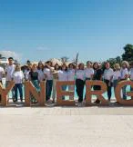 Group of people in front of a large sign that says 'Synergy' 