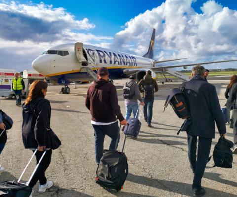 Ryanair passengers board an aircraft with their carry-on baggage