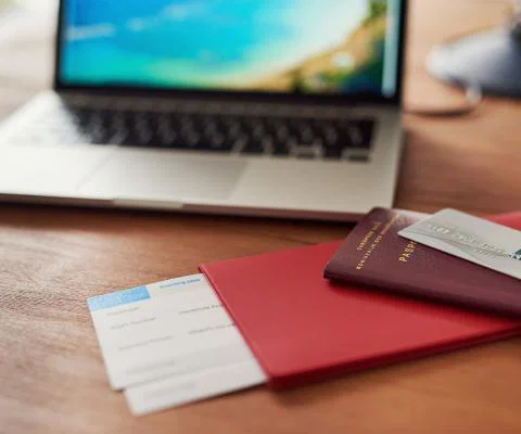 A passport, boarding card and bank card pictured with a laptop in the background