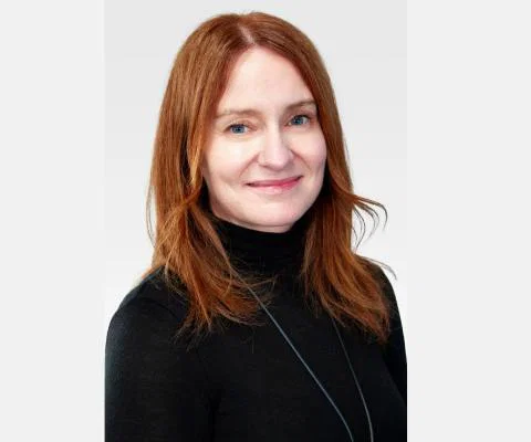 Smiling woman with red long hair and black turtleneck 