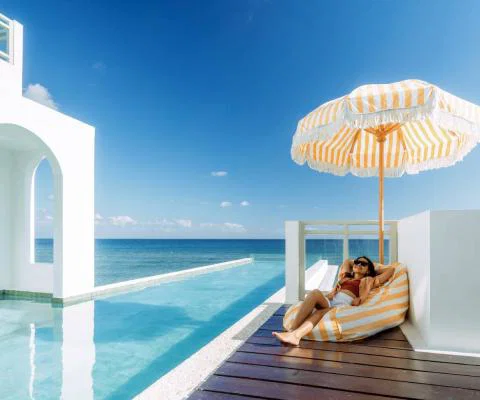 Girl relaxing on sun lounger in beachside resort with infinity pool