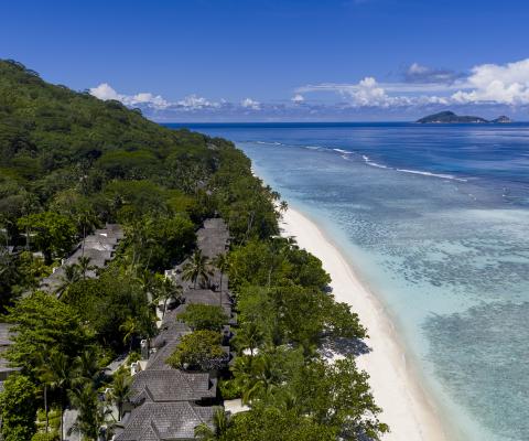 Villas line along a white-sand shoreline with blue oceans and backed by rainforests