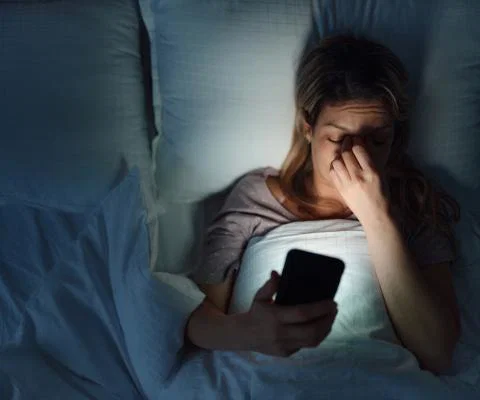 Woman in bed looking at phone