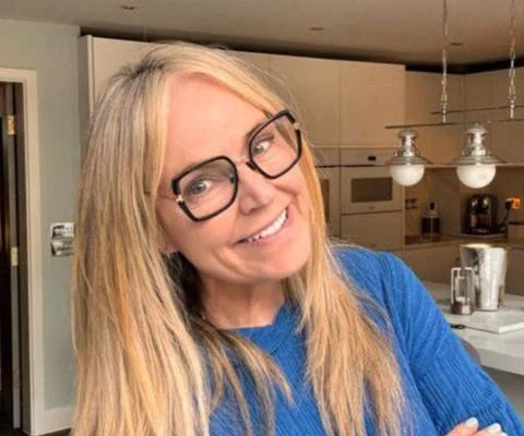 Woman smiling with blonde hair and glasses, her background is a modern kitchen