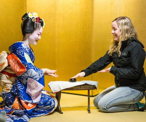 A woman and maiko sitting together smiling