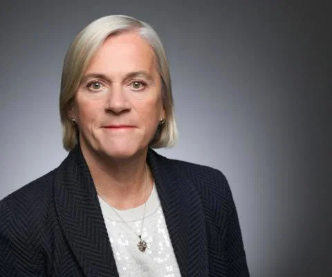 Headshot of middle-aged woman with short blonde hair wearing suit 