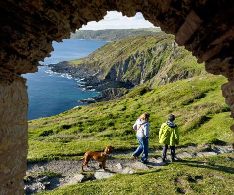A couple with their dog walk along a British coastal path