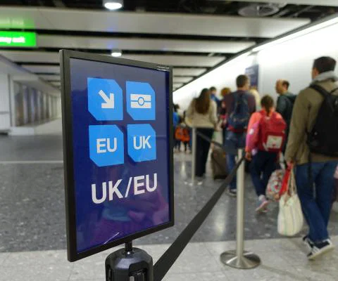 Passengers queue to clear border control at an airport