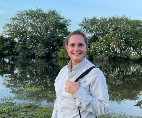 Woman smiles with luscious tree full of Ibis behind her