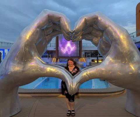 Maria Milne poses besides giant hands shaped in a love heart