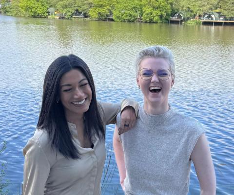 Two women smiling in front of water 