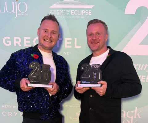 Two men holding trophies and smiling 