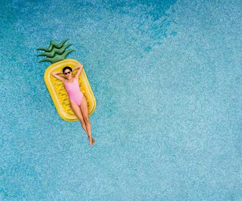 Woman floating on a pineapple lilo