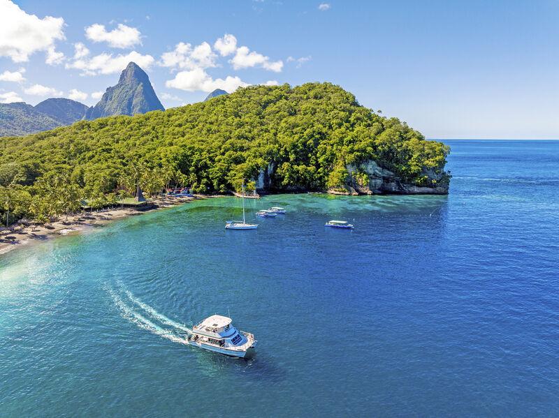 Landscape view of St Lucia with blue ocean, boat, green forest and mountain peak in distance