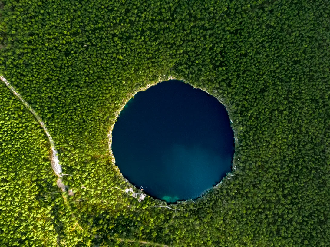 Drone view of circular lagoon surrounded by trees