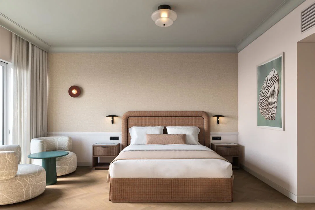 Neutral coloured hotel suite with double bed, sofa and art on wall