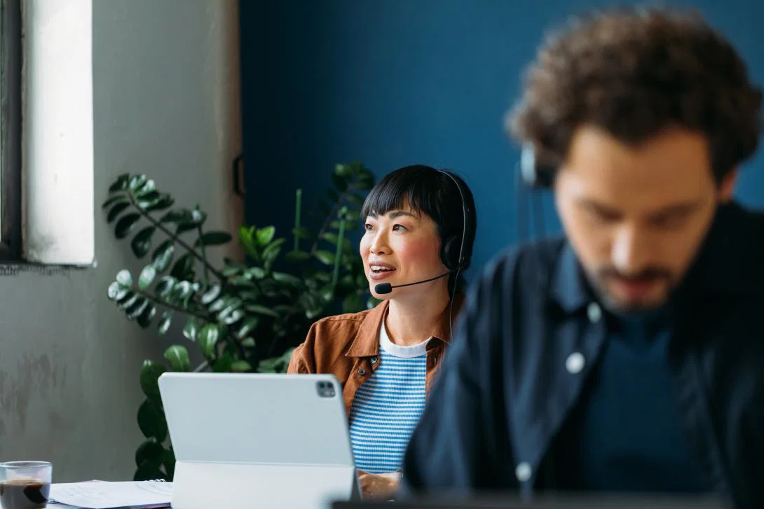 (credit: Lufthansa Group) Woman smiling with headset on with laptop in front of her