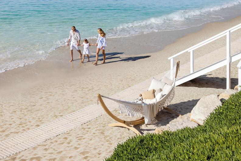 Parents and child walk along a white sand beach 
