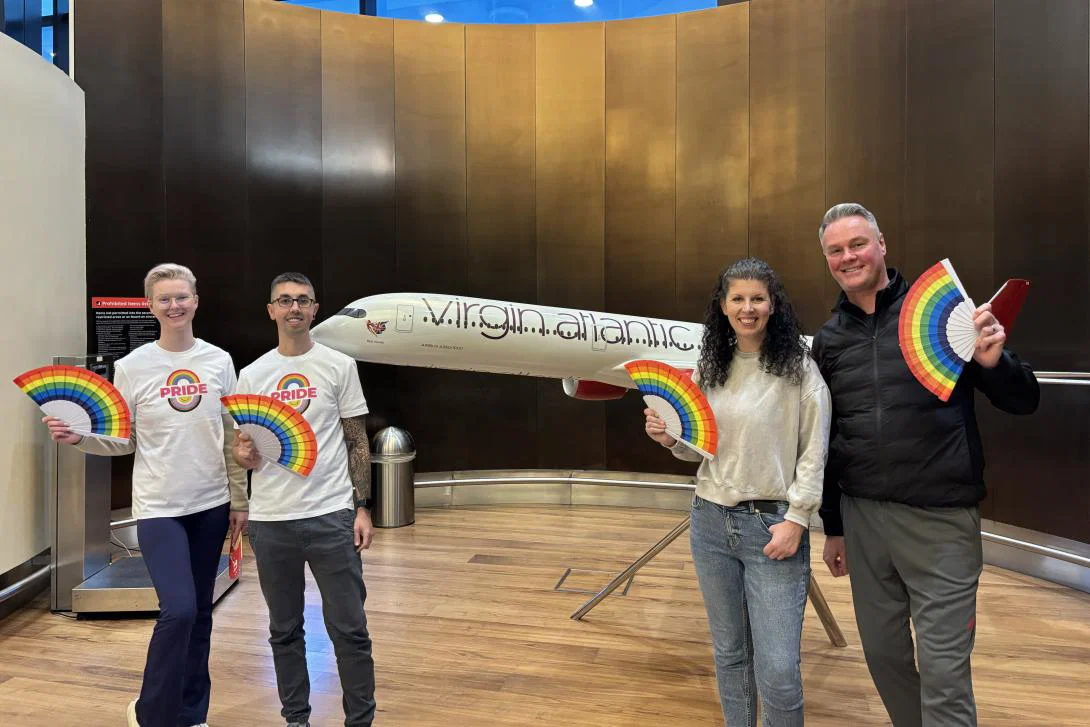 Credit: Jessica Reid Four people standing either side of a mini Virgin Atlantic aircraft holding rainbow-coloured Pride fans