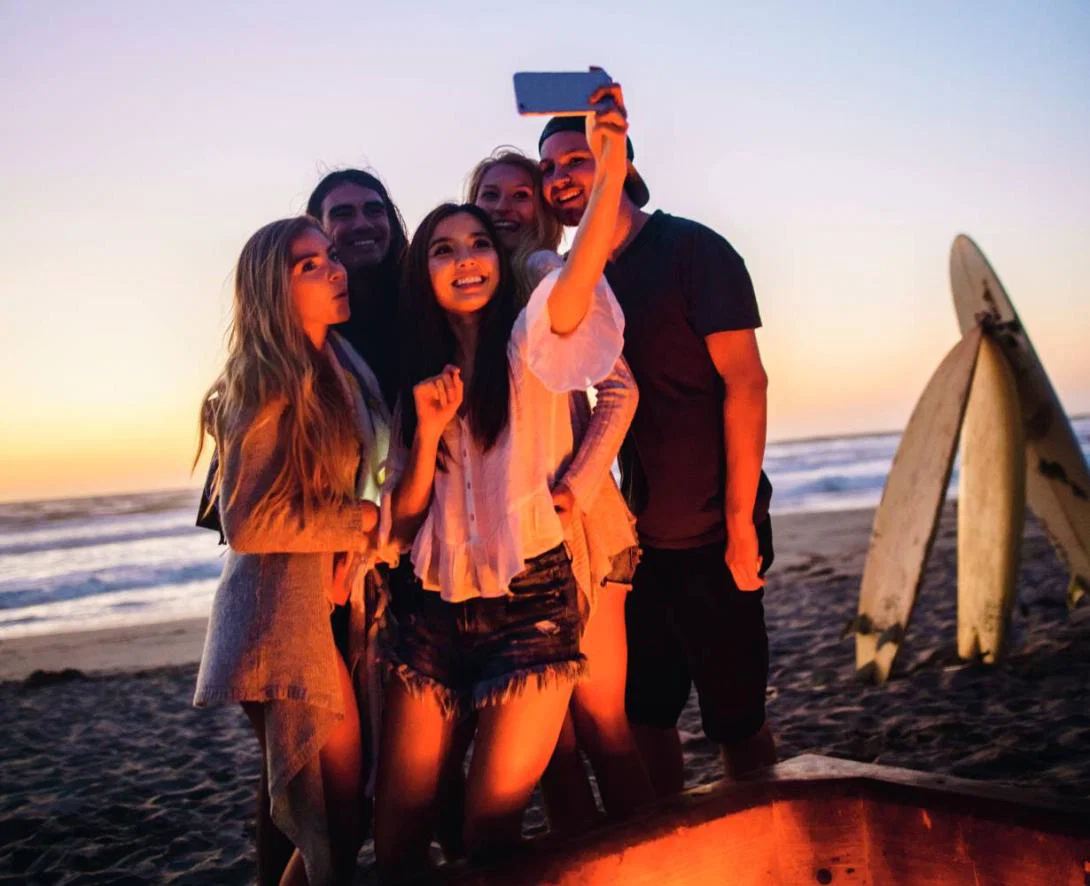Teenagers are increasingly influencing their family's travel choices A group of teenagers on a beach at night taking a selfie